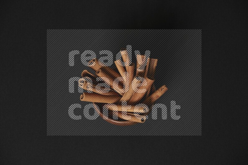 Cinnamon Sticks in a wooden bowl on black background
