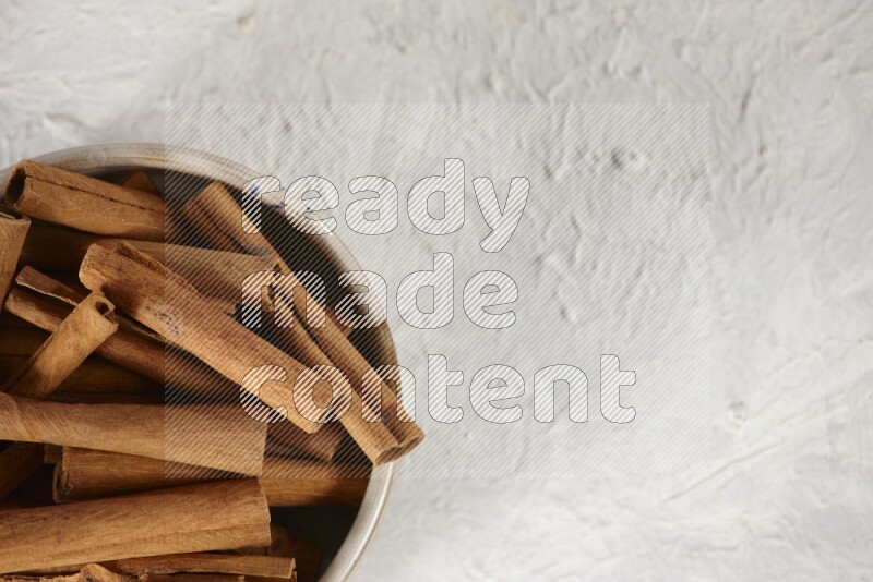 Cinnamon sticks in a ceramic bowl in different angles on white background