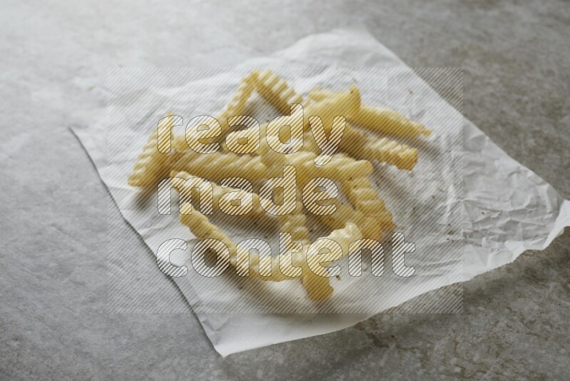 crinkle fries on parchment paper on grey textured counter top