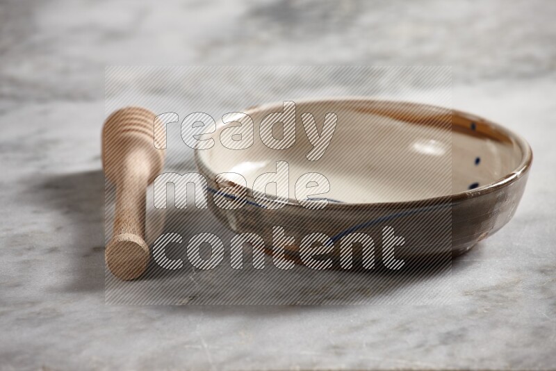 Multicolored pottery bowl with wooden honey dipper on the side on grey marble background