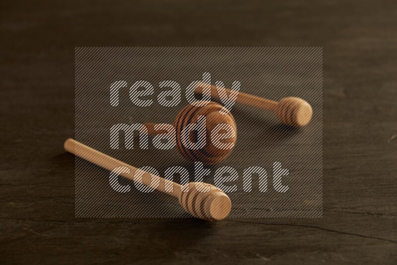 Wooden honey dipper on black slate background