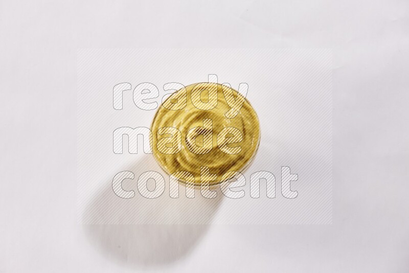 A glass bowl full of mustard paste on a white flooring