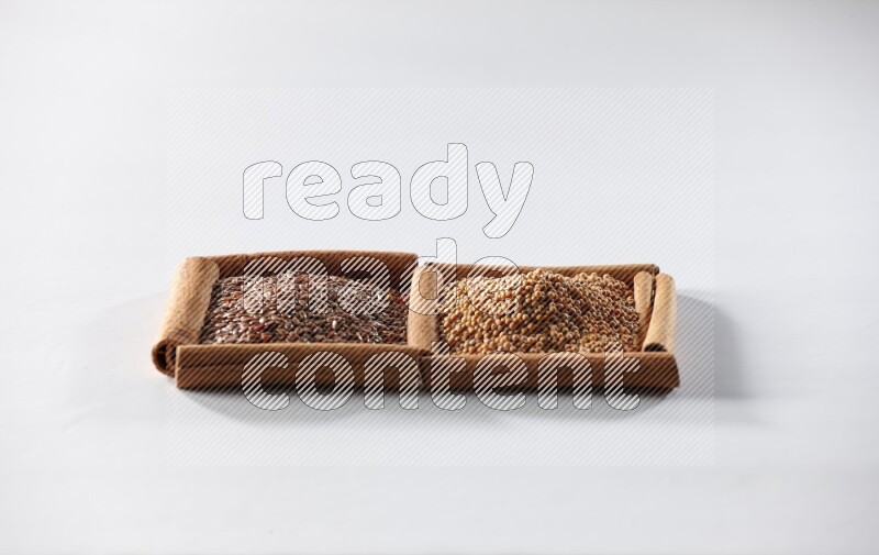 2 squares of cinnamon sticks full of mustard seeds and flaxseeds on white flooring