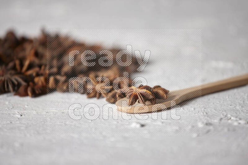 Star anise on a wooden spoon and spreading on the background on a white flooring