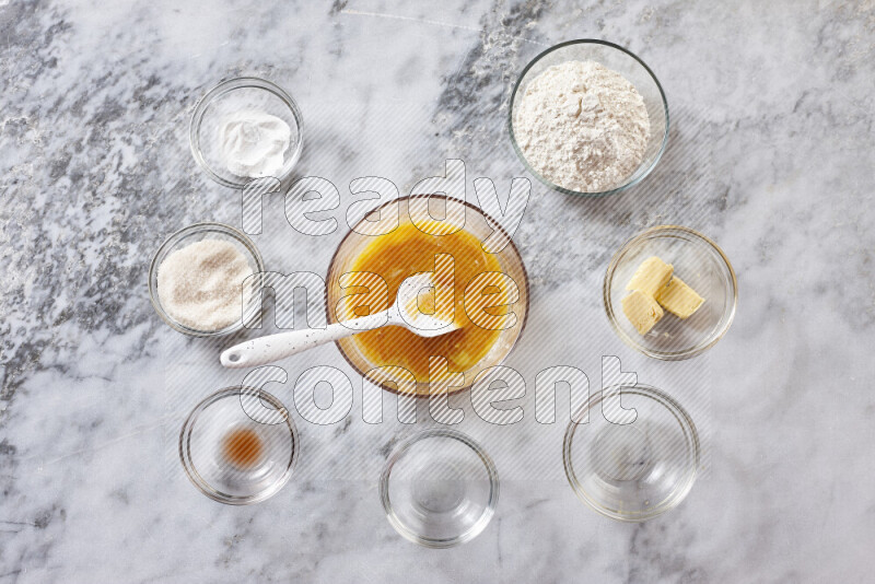 كوكيز خطوة بخطوة بمكوناتها، الدقيق، الزبدة، السكر البني، البيض، الفانيليا، السكر الأبيض، رقائق الشوكولاتة وصودا الخبز على خلفية رخام رمادي