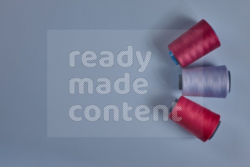 مجموعة من أدوات الخياطة والتفصيل زهرية اللون على خلفية زرقاء