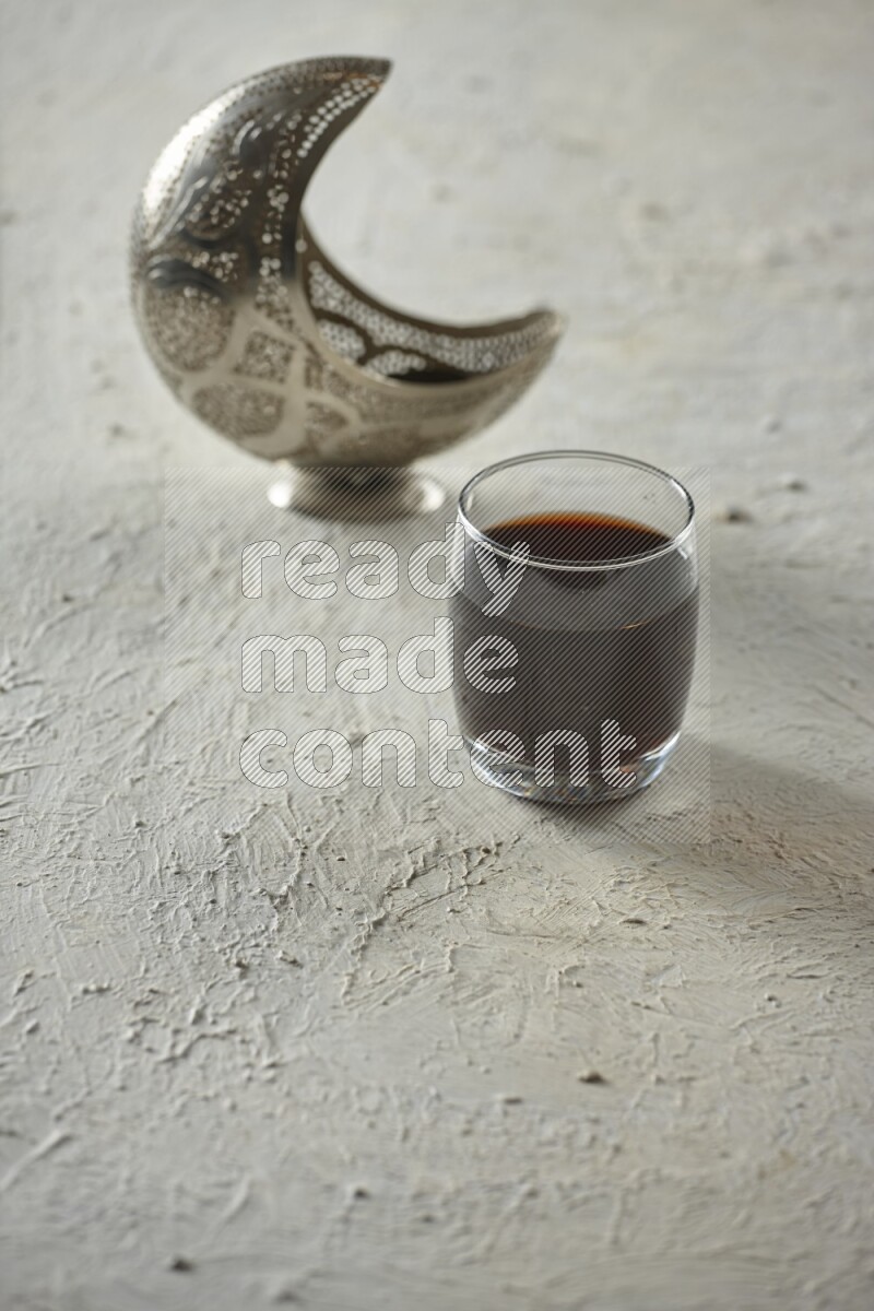 A silver lantern with different drinks, dates, nuts, prayer beads and quran on textured white background
