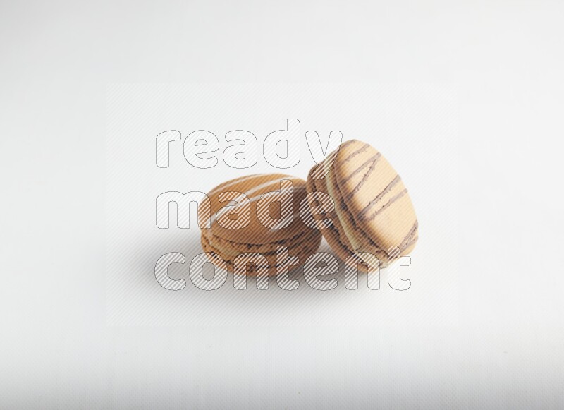 45º Shot of of two assorted Brown Irish Cream, and light brown  Almond Cream macarons on white background