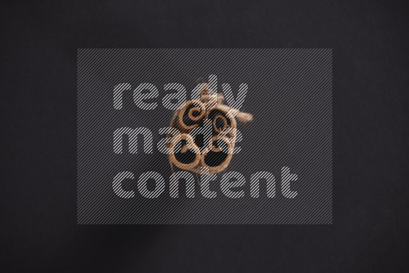 4 أعواد من القرفة مربوطة علي خلفية سوداء