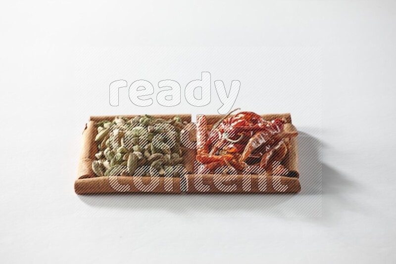 مربعان من أعواد القرفة ممتلئان بحبوب الهيل والفلفل الحار المجفف علي خلفية بيضاء