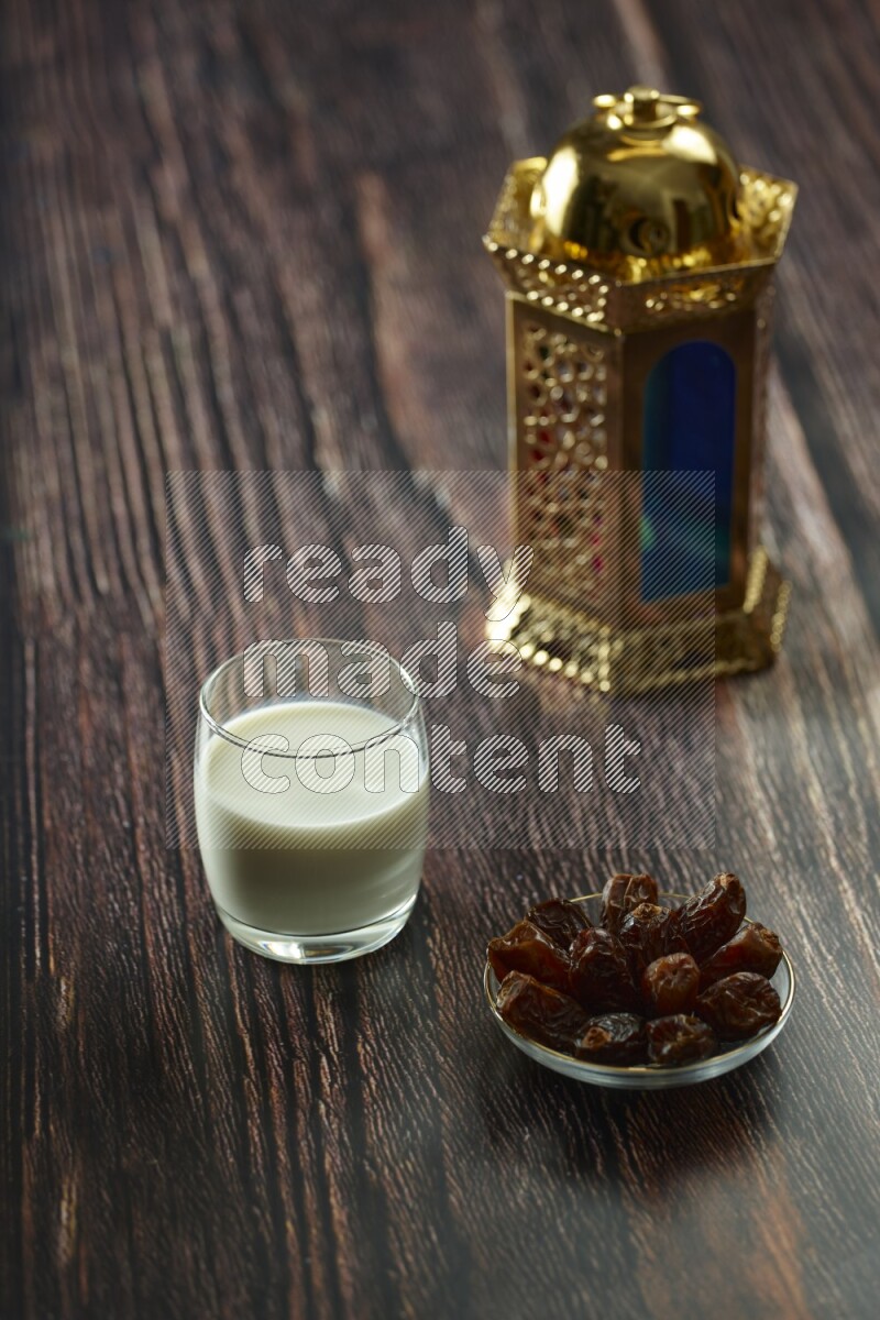 A golden lantern with different drinks, dates, nuts, prayer beads and quran on brown wooden background