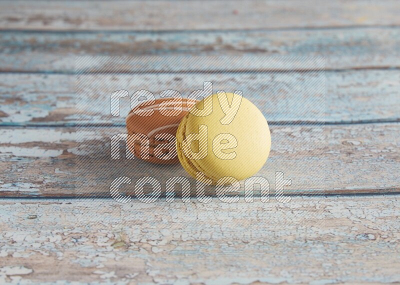 45º Shot of of two assorted Brown Irish Cream, and Yellow Lime macarons on light blue background