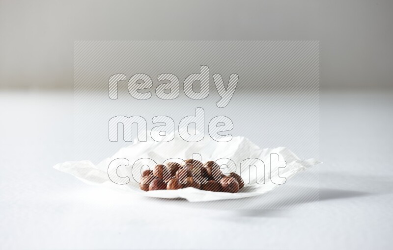 Peeled hazelnuts on a crumpled piece of paper on a white background in different angles