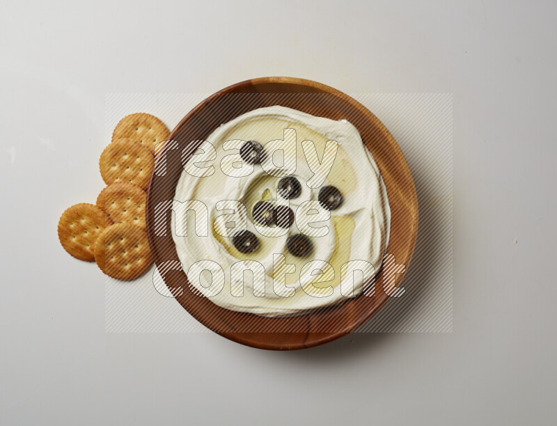 Lebnah garnished with sliced olives in a wooden plate on a white background