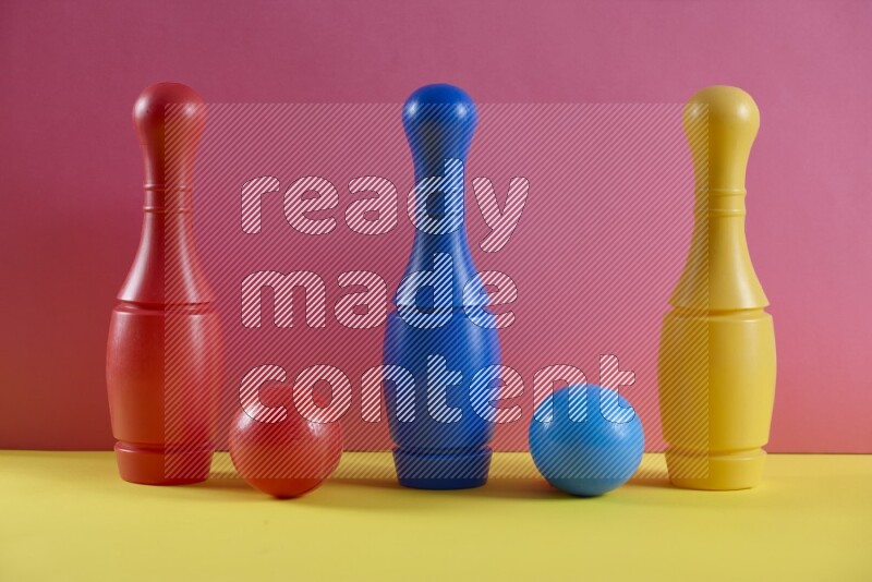 Plastic bowling pins with balls on pink and yellow background (kids toys)