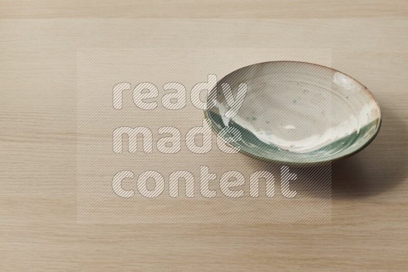 A multicolored pottery plate on light wooden background