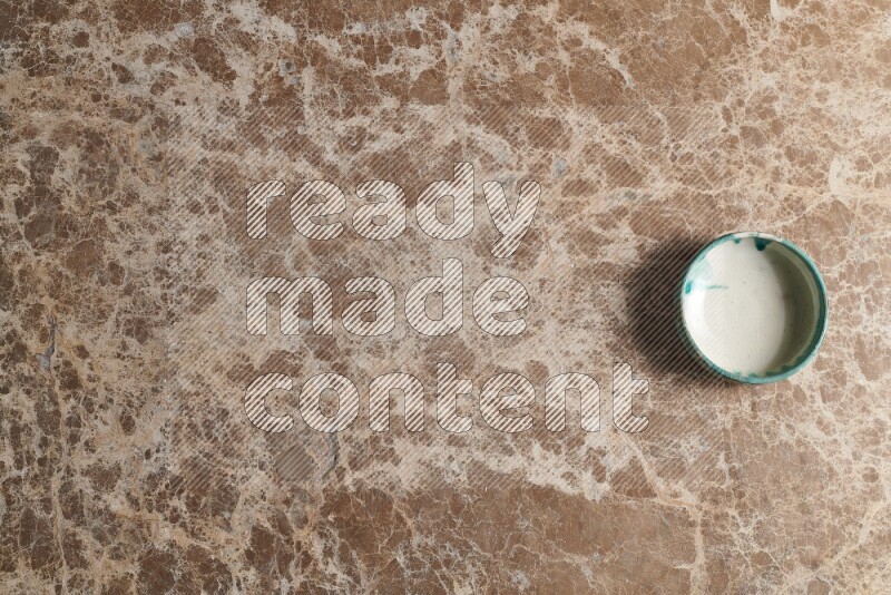 A multicolored pottery bowl on beige marble background