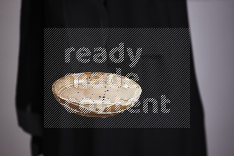 امرأة ترتدي عباءة سوداء تحمل أدوات فخارية مختلفة في أوضاع متعددة