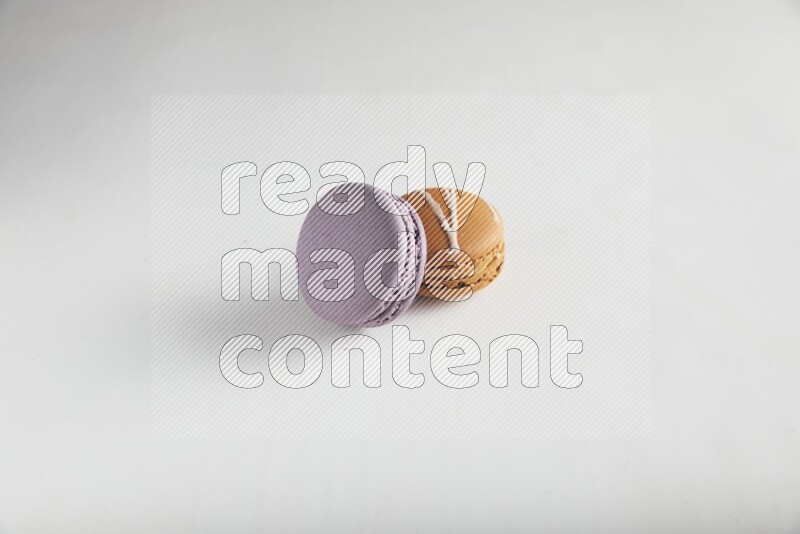 45º Shot of of two assorted Brown Irish Cream, and Purple Blueberry macarons on white background