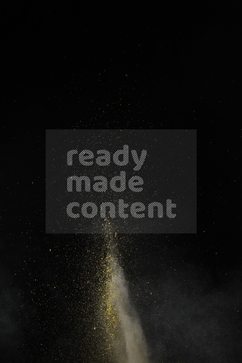 A side view of yellow powder explosion on black background