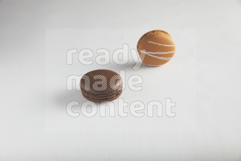 45º Shot of of two assorted Brown Irish Cream, and Brown Dark Chocolate macarons on white background