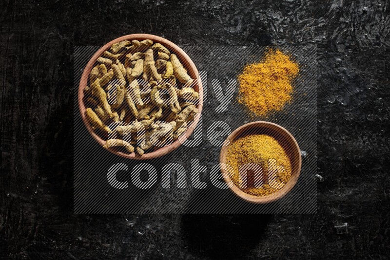وعاءان خشبيان، أحدهما ممتلئ ببودرة الكركم والآخر بأصابع الكركم المجففة، على خلفية سوداء
