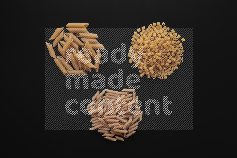 Different pasta types in bunches on black background