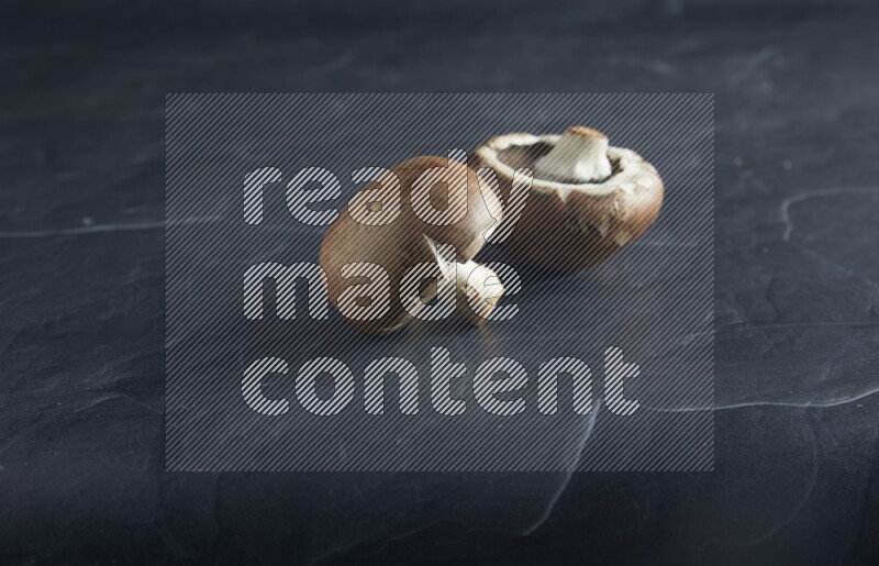 45 degre cremini  mushrooms on a textured black slate background