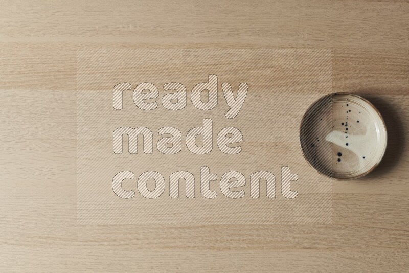 صحن فخاري متعدد الألوان على خلفية خشبية فاتحة