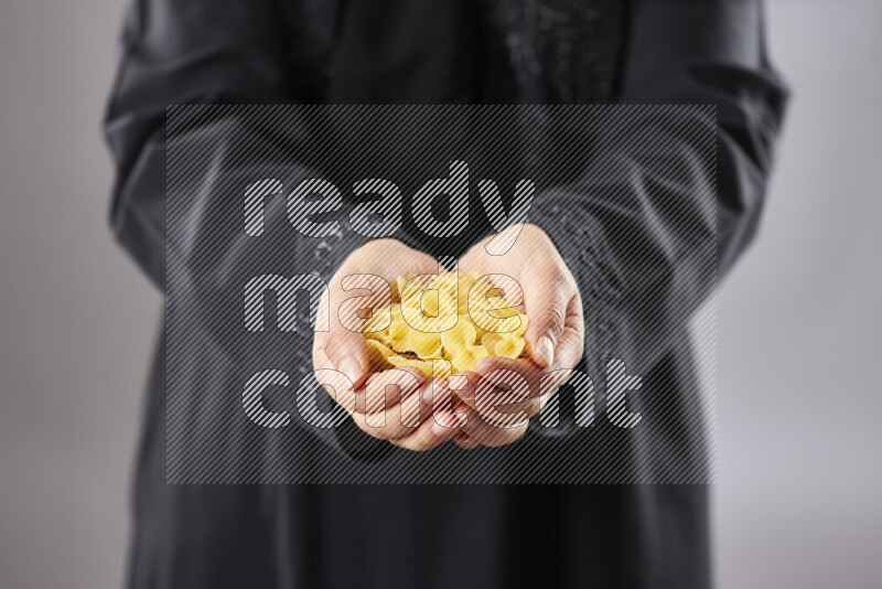 Woman in abaya holding different kinds of pasta in different positions