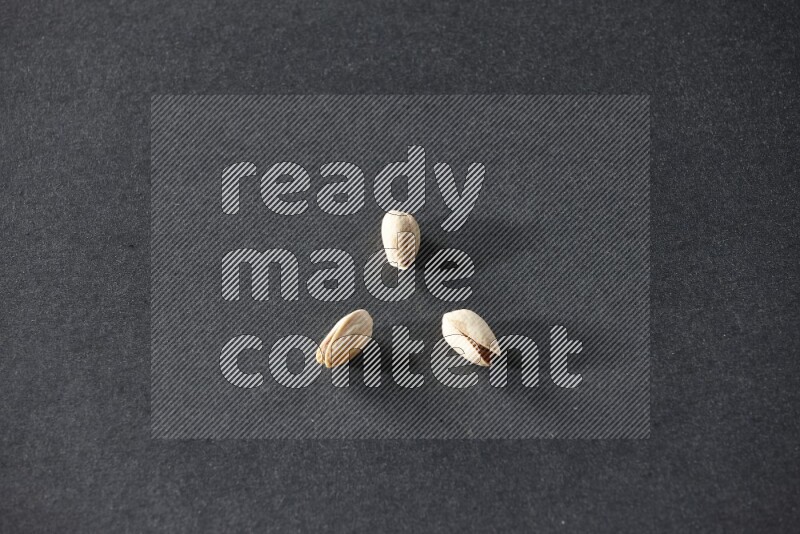 3 pistachios on a black background in different angles