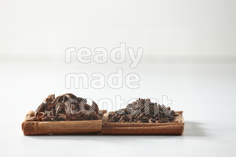 2 squares of cinnamon sticks full of cloves and star anise on white flooring