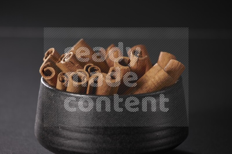 أعواد القرفة في وعاء فخاري أسود علي خلفية سوداء