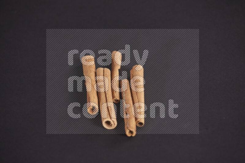 Cinnamon sticks stacked on black flooring