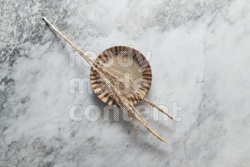 Wheat stalks on multicolored pottery plate on grey marble background