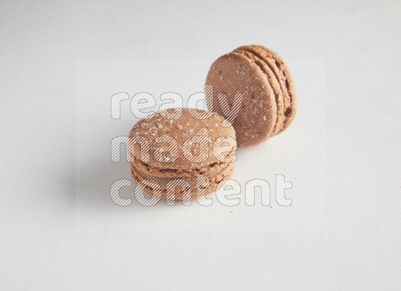 45º Shot of two Brown Hazelnuts macarons on white background