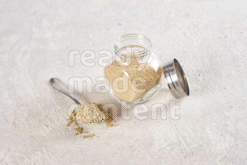 A glass jar full of ground ginger powder on white background