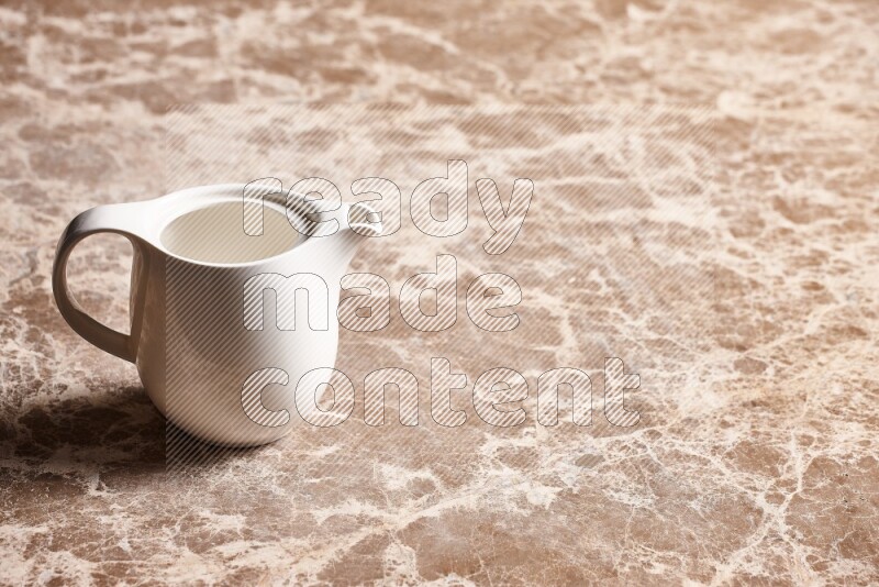 A ceramic milk jug on beige marble background