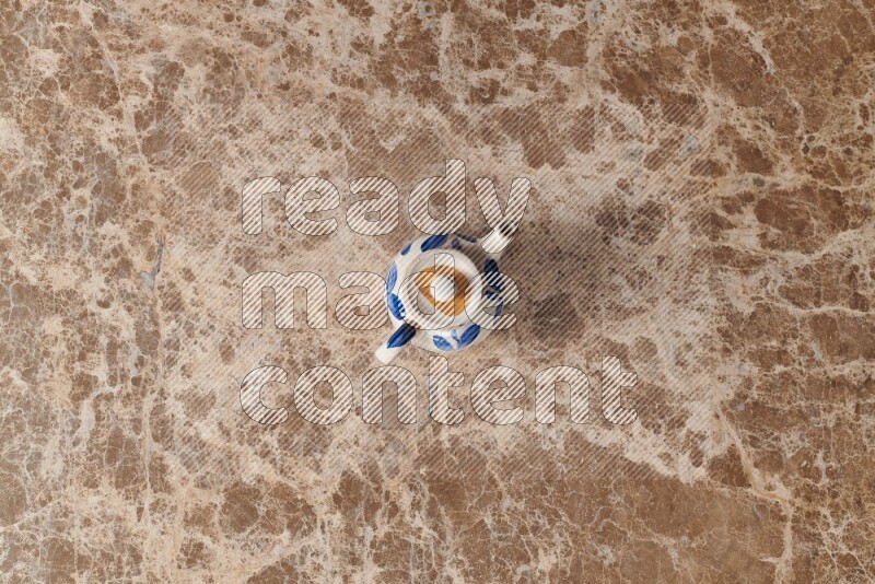 A pottery teapot on beige marble background