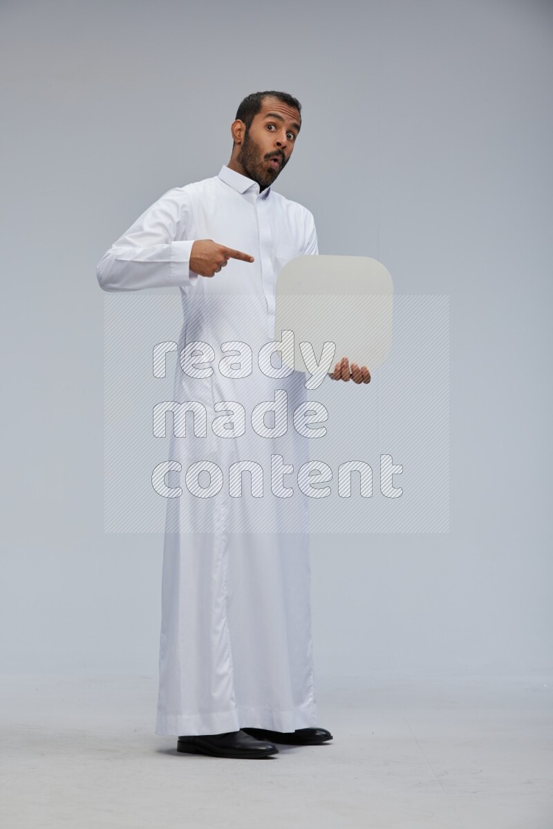 Saudi man wearing Thob standing holding social media sign on Gray background