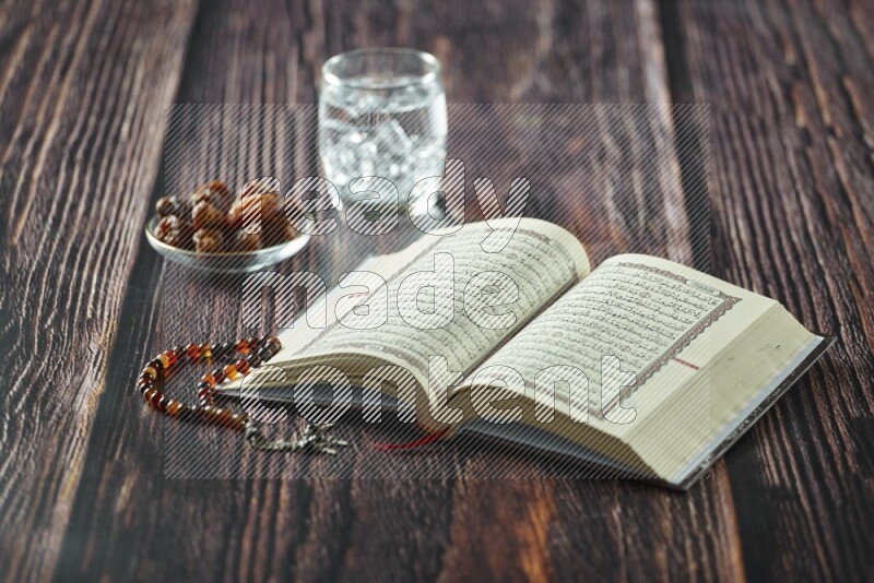 Quran with dates, prayer beads and different drinks all placed on wooden background