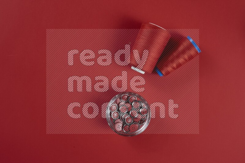 A red collection of sewing and tailoring tools arranged on a red background