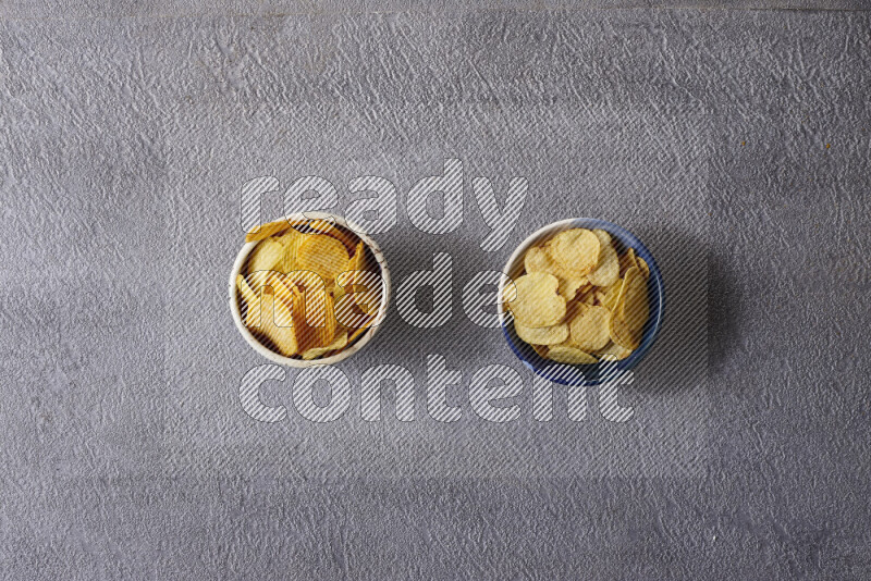 Assorted snacks in pottery bowls on grey background