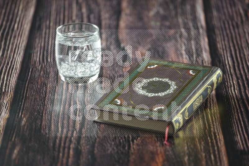 Quran with dates, prayer beads and different drinks all placed on wooden background
