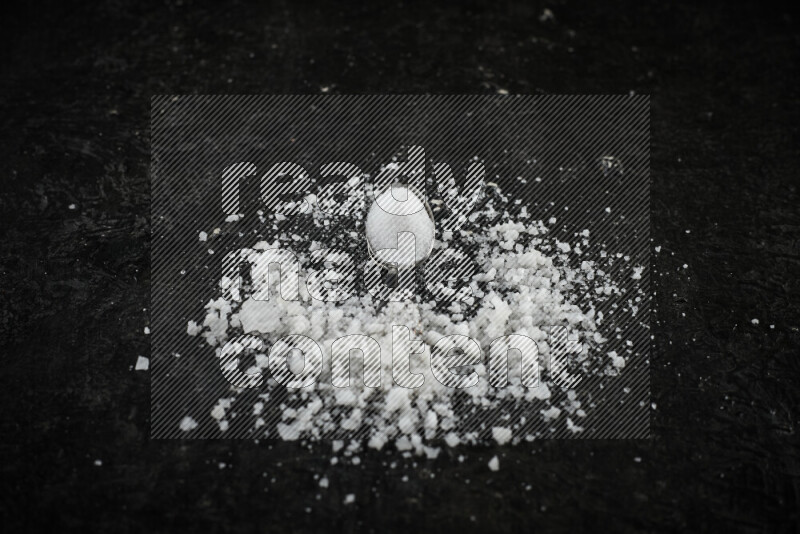 2 metal spoons filled with white salt on black background