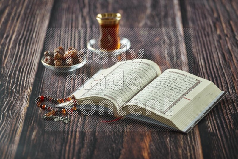 Quran with dates, prayer beads and different drinks all placed on wooden background
