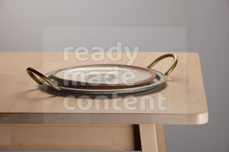 multicolored plate placed on a rounded stainless steel tray with golden handels on the edge of wooden table