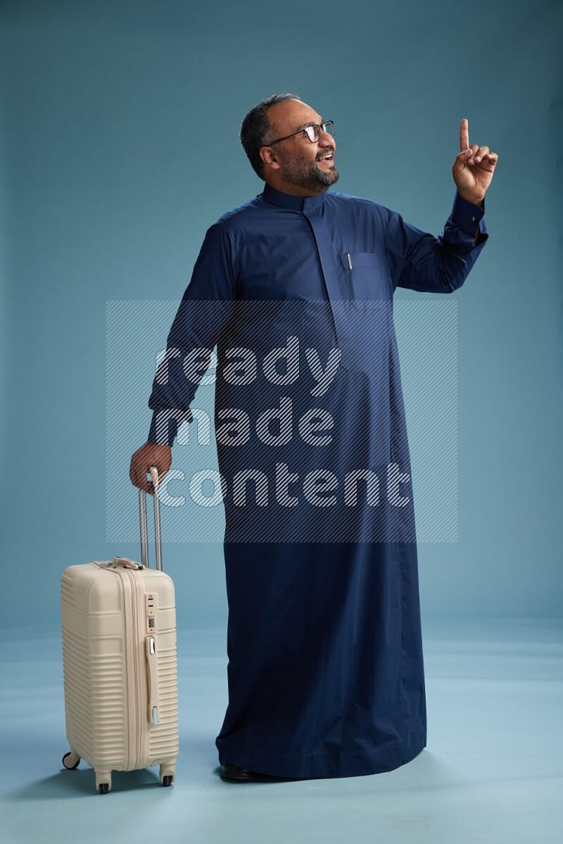 Saudi Man without shimag Standing pulling travel bag on blue background