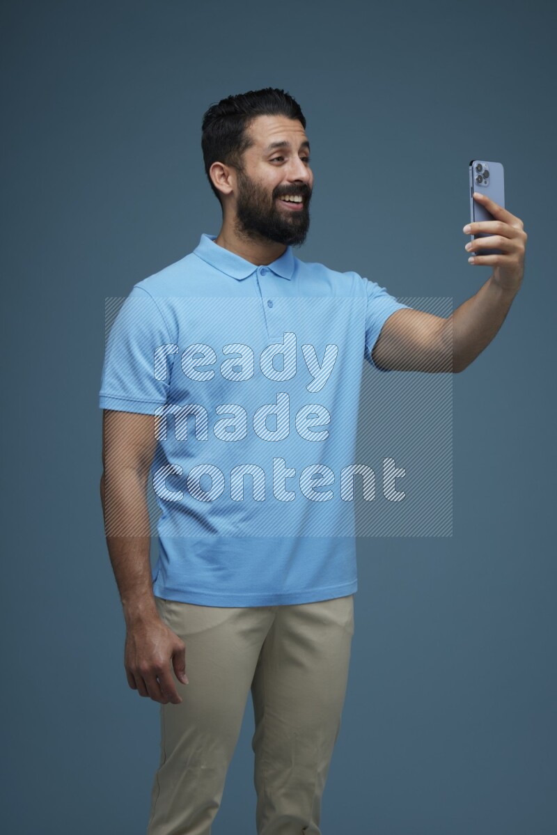 Man Taking a Selfie in a blue background wearing a Blue shirt