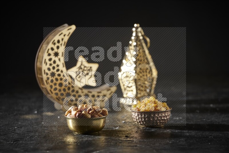 Nuts in a metal bowl with raisins beside golden lanterns in a dark setup
